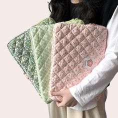 a woman holding four pieces of quilted material