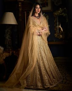 This lehenga set features heavy gold embroidery in a linear pattern. The full sleeves blouse has a plunging neckline. The lehenga set shows delicate pearl, gold beaded detail at the neckline, waist and wrist. It is paired with a fully embroidered dupatta. DELIVERY TIMEPlease allow 8-12 weeks for your outfit to arrive. FABRIC DETAILSLehenga - Net / Dupatta - Net Professional cleaning only. Beaded Lehenga, Golden Bridal Lehenga, Scalloped Dupatta, Full Sleeves Blouse, Gold Sequin Jacket, Pearl Mirror, Polygon Pattern, Sequin Lehenga, Jacket Lehenga