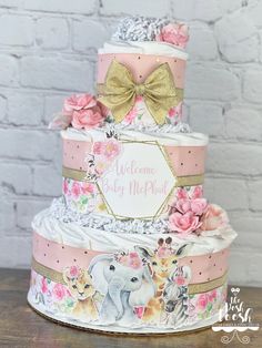 a three tiered cake decorated with flowers and an elephant on the top is pink, gold and white