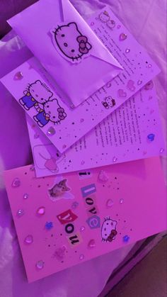 hello kitty birthday cards and envelopes are laying on a bed sheet with pink sheets