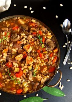 a bowl of soup with mushrooms, carrots and other vegetables on a black surface