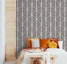 a white bed sitting next to a wall with black and white designs on the walls