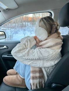 a woman sitting in the back seat of a car with her head down and wearing a scarf