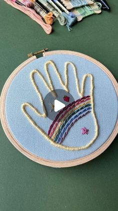 a hand embroidered onto a piece of fabric next to some scissors and thread on a green surface