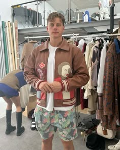 a young man standing in front of a rack of shirts and shorts with a monkey on it