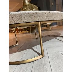 a marble top coffee table with metal legs and a gold vase sitting on it's side