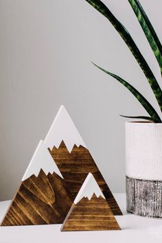 three wooden mountains are sitting next to a potted plant on a white countertop