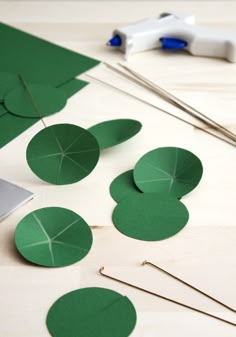 several pieces of green paper sitting on top of a table next to scissors and thread