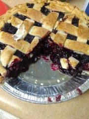 a pie sitting on top of a pan covered in blueberry toppings and cut in half