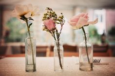 three vases with flowers in them sitting on a table