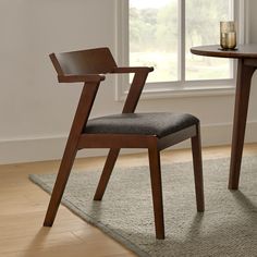 a chair sitting in front of a table with a candle on top of it next to a window