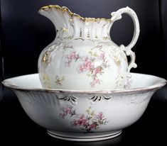 a white vase sitting inside of a bowl on top of a table next to a black background