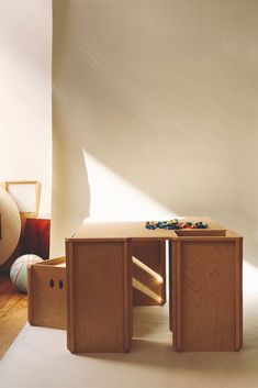 a child's wooden table with toys on it in front of a white wall