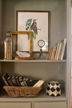 a bookshelf with baskets and pictures on it in a home office area that is painted gray