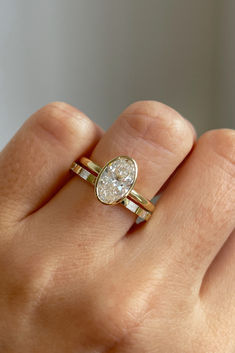 a woman's hand holding a ring with a pear shaped diamond on top of it