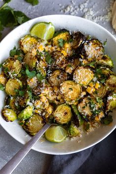 a white bowl filled with brussel sprouts and lime