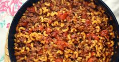 a skillet filled with pasta and ground beef in sauce on top of a table