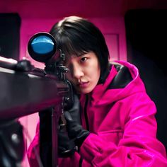 a woman in a pink jacket looking through a telescope