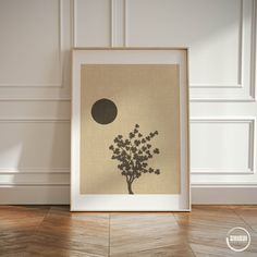 an art print with a tree in the middle and a moon above it on a wood floor