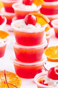 small cups filled with fruit and whipped cream on top of oranges, cherries, and strawberries