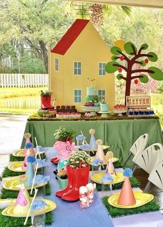 a table set up for a party with plates and cups on it, near a house