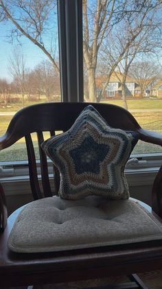 a wooden chair with a pillow on it in front of a window