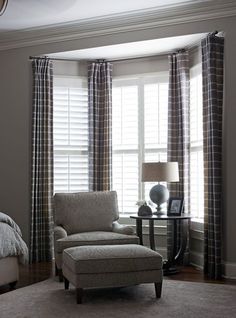 a chair and ottoman in front of two windows