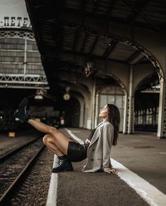 a woman is sitting on the train tracks and looking up at her legs as she sits down