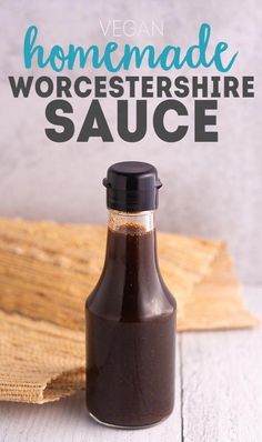 a glass bottle filled with sauce sitting on top of a wooden table