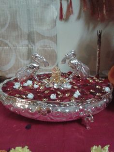 an ornately decorated dish on a red table cloth with silverware in the background