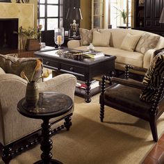 a living room filled with furniture and a fire place under a chandelier in front of a window