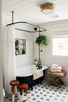 a black and white bathtub in a bathroom with two stools next to it