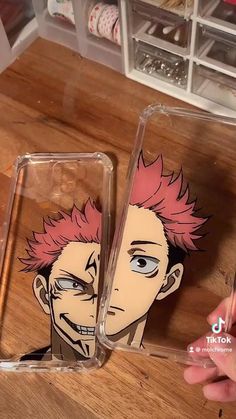 two cases with anime characters on them sitting next to each other in front of a wooden table