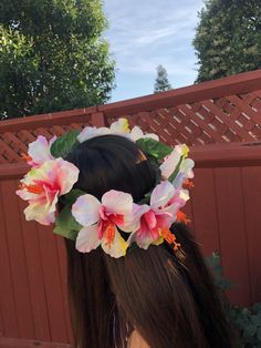 a woman with long hair wearing a flower crown on her head, in front of a fence