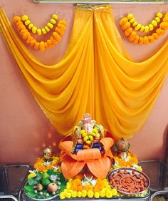 there is an idol in front of the yellow drapes and flowers on the wall