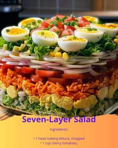 a layered salad with hard boiled eggs, tomatoes, lettuce, onions and other veggies