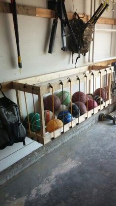 there are many balls in the storage area on the wall behind the bike rack, which is holding several pairs of skis