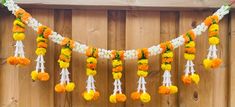 an orange and white garland with flowers hanging from it's side on a wooden wall