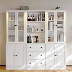 a white bookcase filled with lots of books next to a wall mounted shelf full of liquor bottles