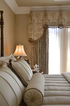 a large bed sitting in the middle of a bedroom next to a window with curtains