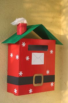 a red mailbox with a green roof and santa clause on the top, sitting against a yellow wall