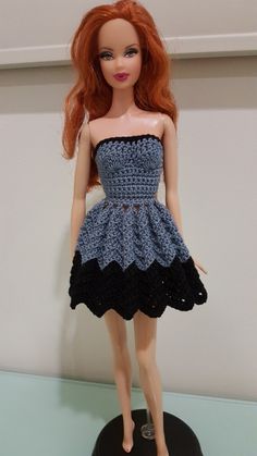 a doll with red hair wearing a blue and black crochet dress on display