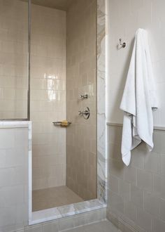 a walk in shower sitting next to a white towel on top of a bath tub