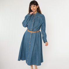 Vintage 90s dress in blue denim with a high waist and a belt. It features buttons up the front, pockets, and pleating on the chest. Midi length. Please see measurements and condition below. Every garment we sell is authentic vintage and one-of-a-kind! You will receive the exact item photographed. Condition: Very good vintage with light general wear. Has some fading on the back. Size label: Labelled 14 Tag: Nina Piccalino Material: 100 Cotton Era: 90s MEASUREMENTS Taken from seam to seam while the garment is lying flat. Double the armpit, waist, and hips For reference, model is 5'9" and measures 34-27-39. Length from Top: 49" Armpit to Armpit: 23" Waist: 16" Hips: 27" Shoulder to Shoulder: 17" Sleeve: 25" For sales and promotions, follow us @Shopexile *241002260* Jean Shirt Dress, Vintage 90s Dress, Blue Jean Dress, Midi Dress Blue, Denim Midi Dress, 90s Denim, 90s Dress, Size Label, Blue Midi Dress