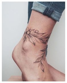 a woman's foot with a flower tattoo on the side of her leg and ankle