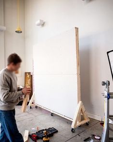 a man standing next to a white board in a room filled with construction supplies and tools