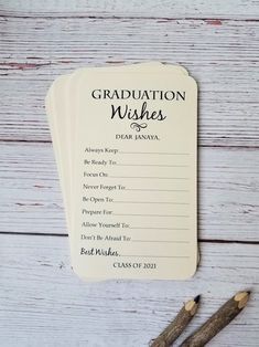 graduation wishes card with two pencils next to it on a white wooden table top