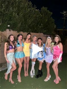 a group of young women standing next to each other in front of a fence at night