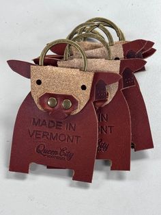 three leather tags with metal handles on each one that says made in vermont and the other has a cow's head sticking out of it