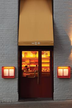 an open door to a restaurant with red lights on the outside and yellow windows above it